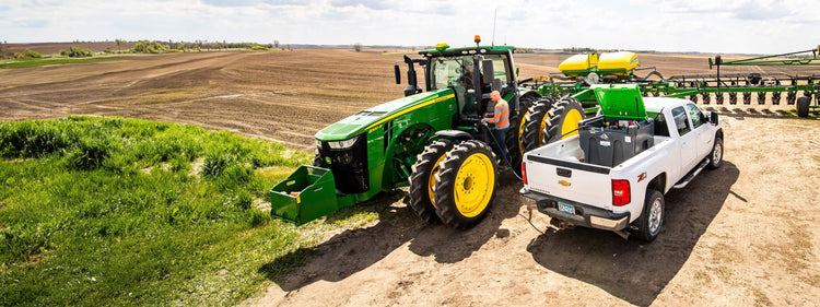 Pickup Truck With Storage Tank Refilling Tractor in Field